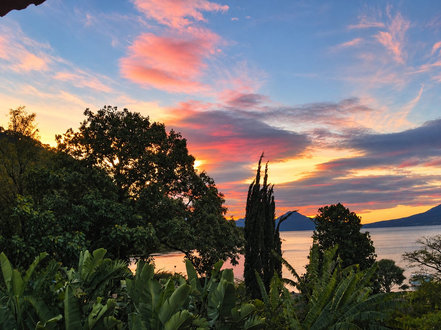Tramonto sul Lago Atitlán con alberi davanti